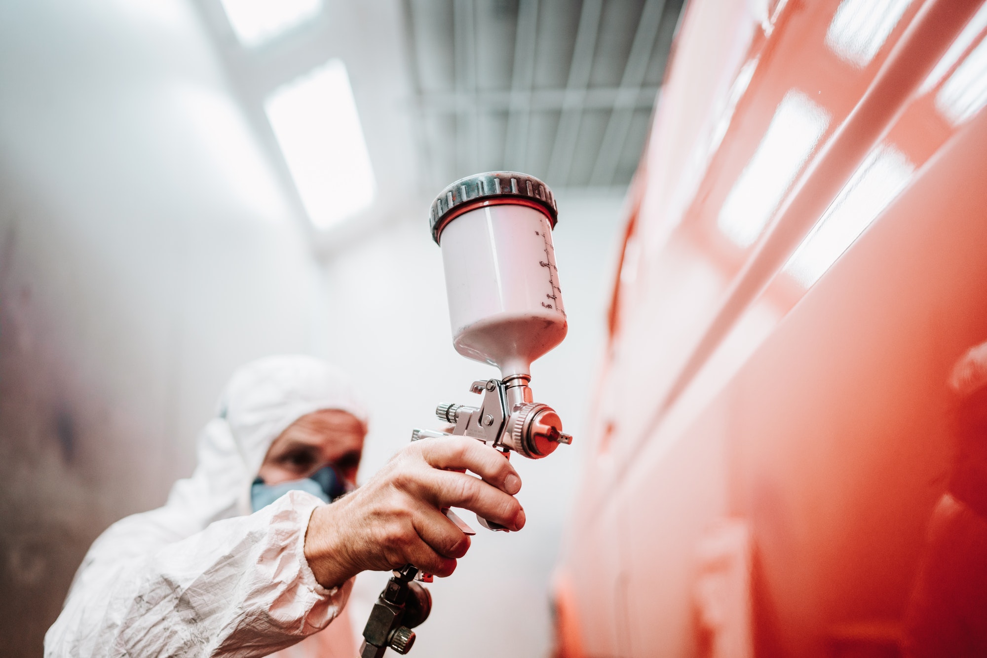 close up of paint spray gun, worker painting a car